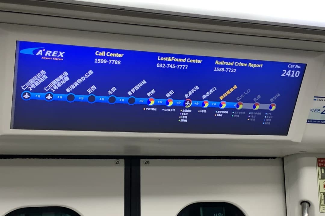 Route display above the doors of an AREX train showing the stations and the airport symbol