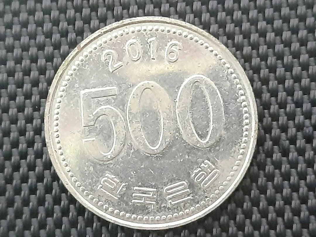 A silver 500 won coin photographed from above on a dark textured background