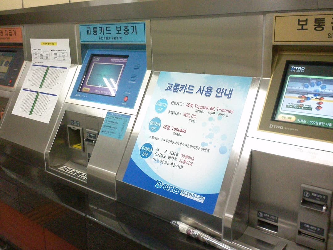 A transit-card top-up machine in a Korean station with a notice about which cards it accepts