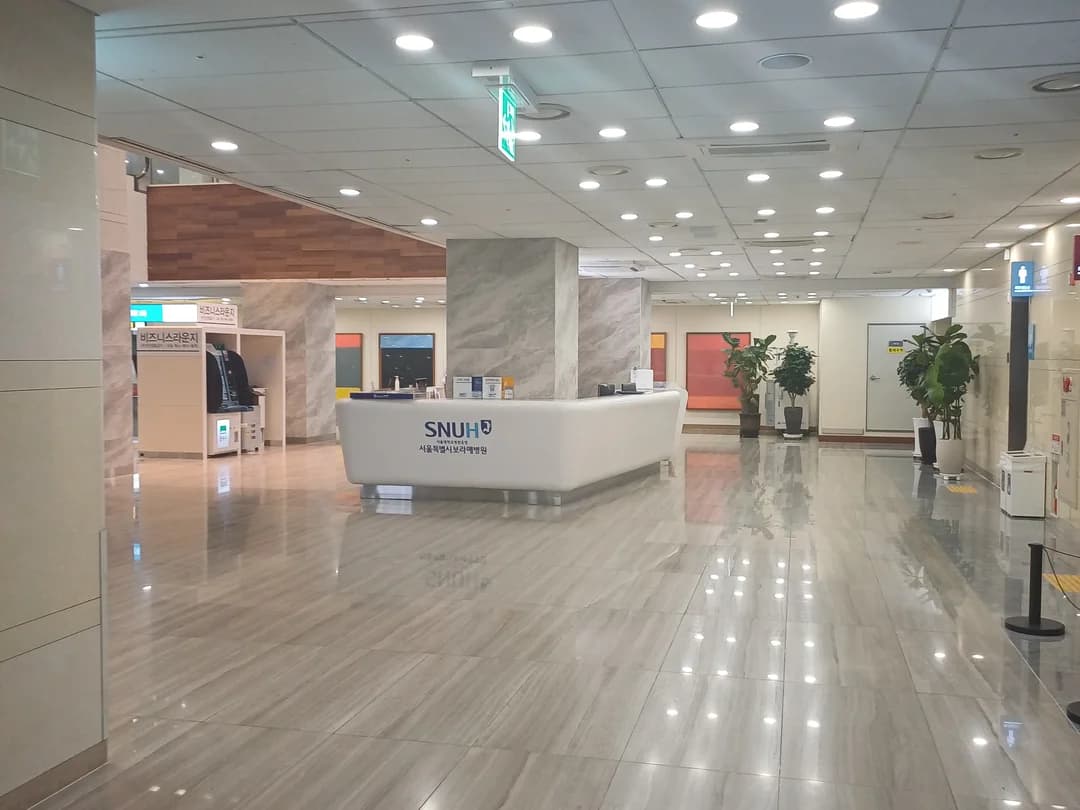 A bright hospital lobby with a reception desk and a polished floor